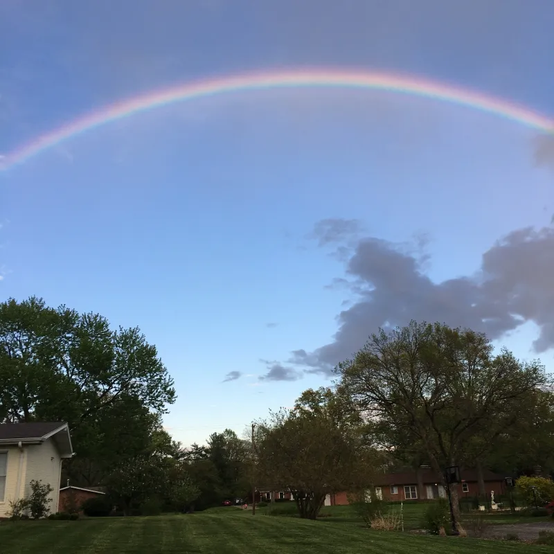 A rainbow is seen in the sky over a house.