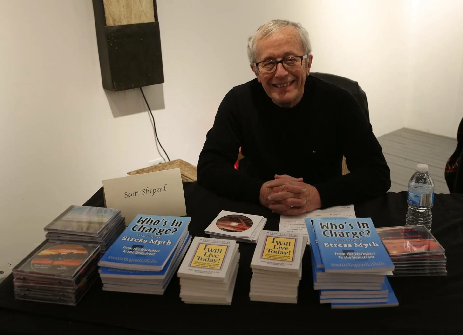 A man sitting at a table with several books on it.