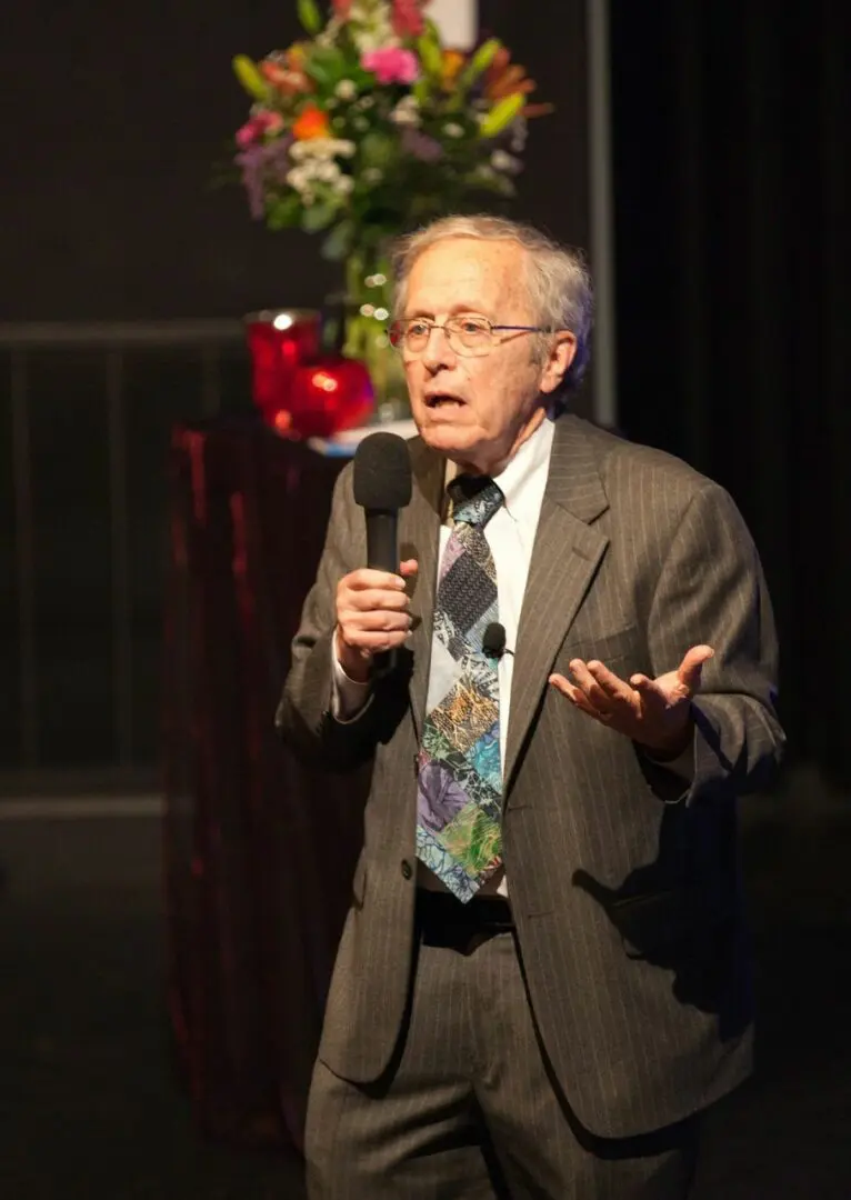 A man in suit and tie holding a microphone.